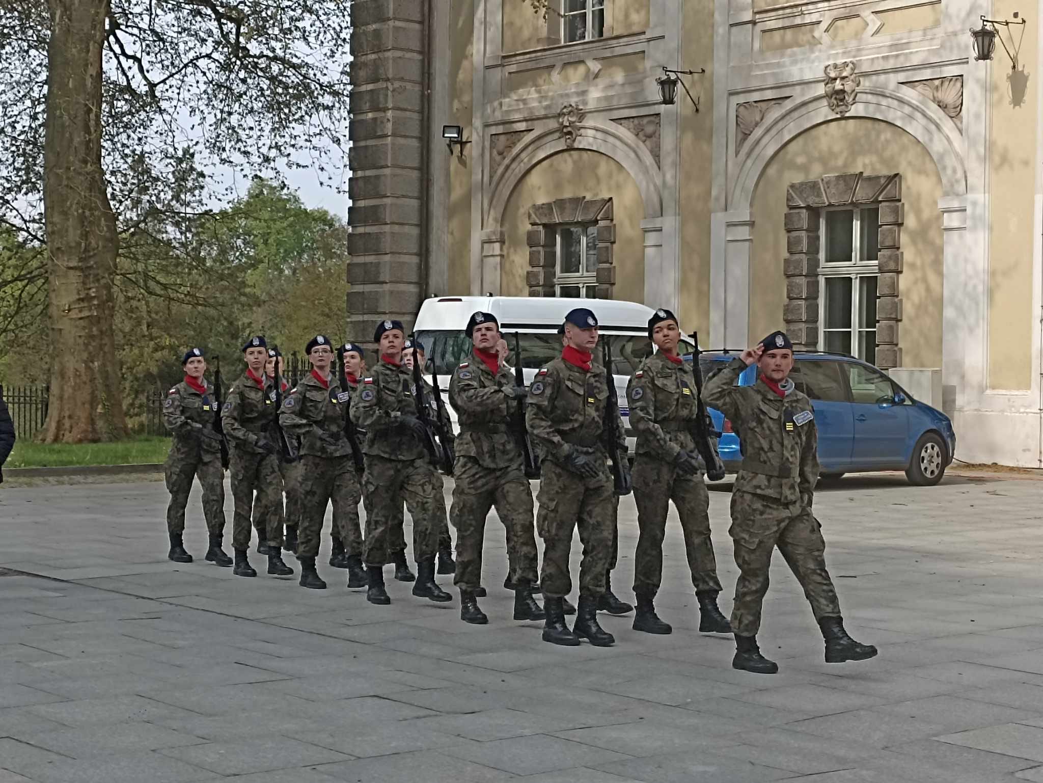 Grupa żołnierzy maszeruje środkiem ulicy 