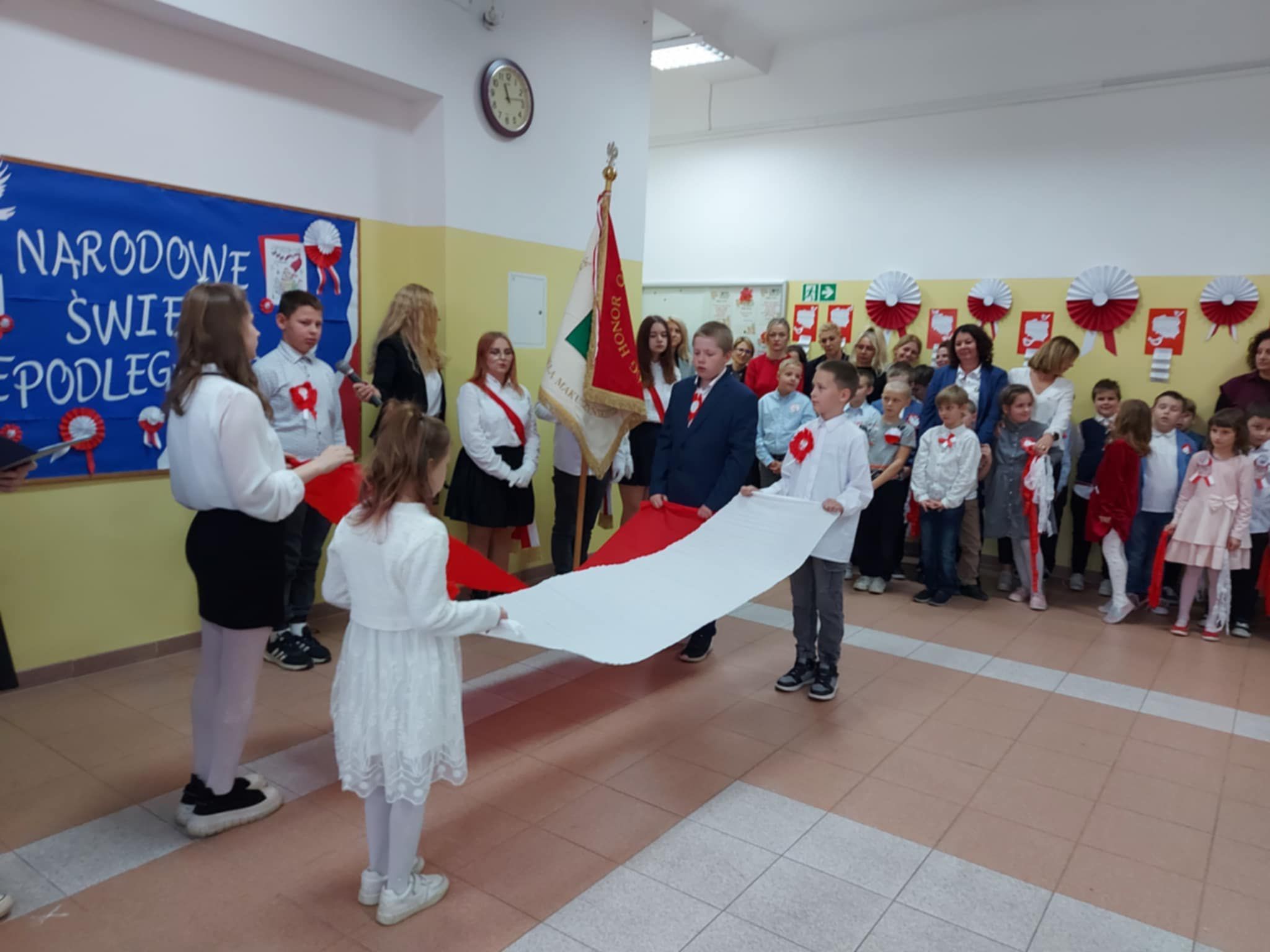 Na obrazku widać grupę osób, flagę biało- czerwoną