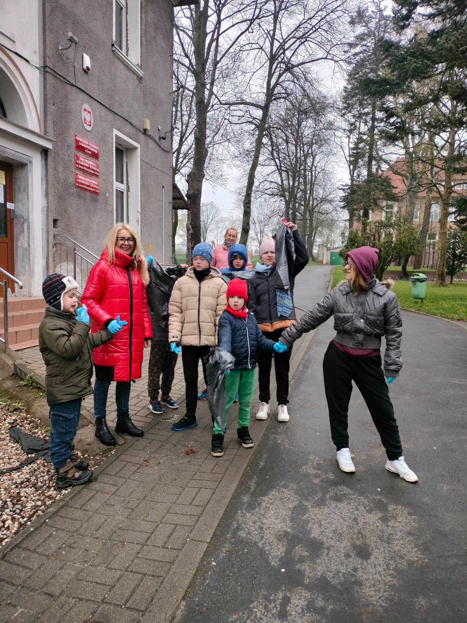 Obok budynku stoi grupa osób
