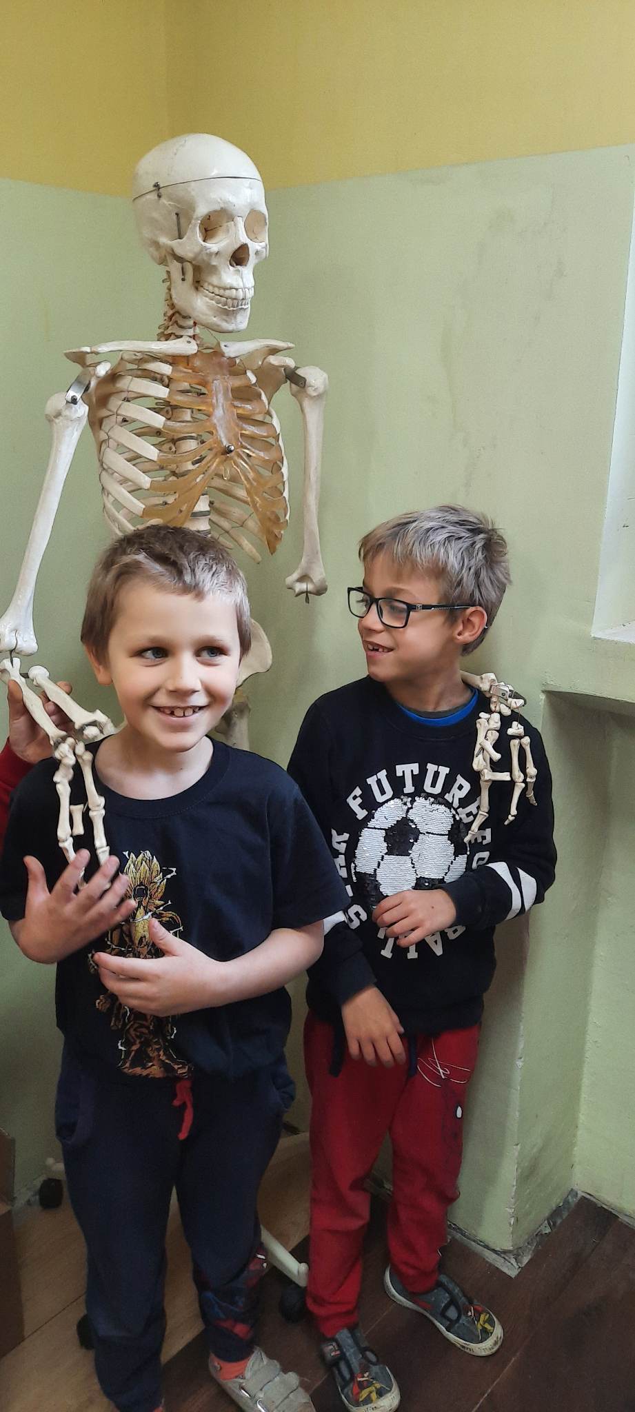 2 osoby stoją przy szkielecie człowieka 