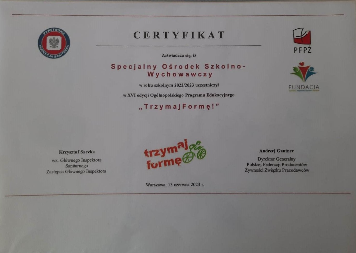W środku napisy, po bokach i na dole  symbole graficzne