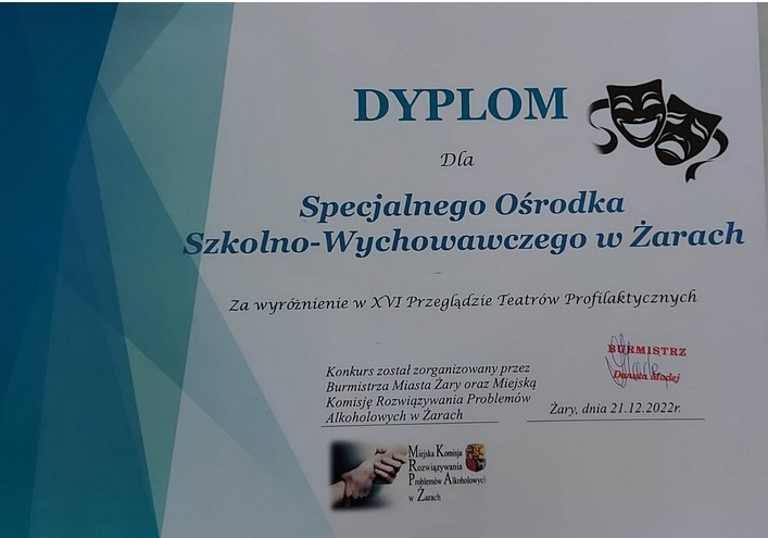 W środku tekst, po prawej stronie niebieskie trójkąty, po lewej stronie maski teatralne.
