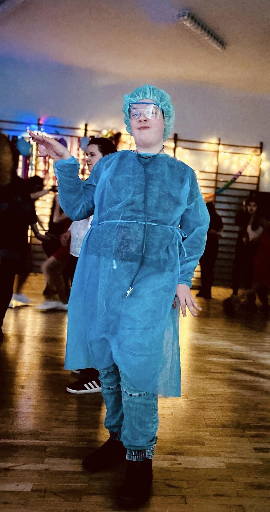 W sali stoi osoba , w tle znajduje się grupa osób 