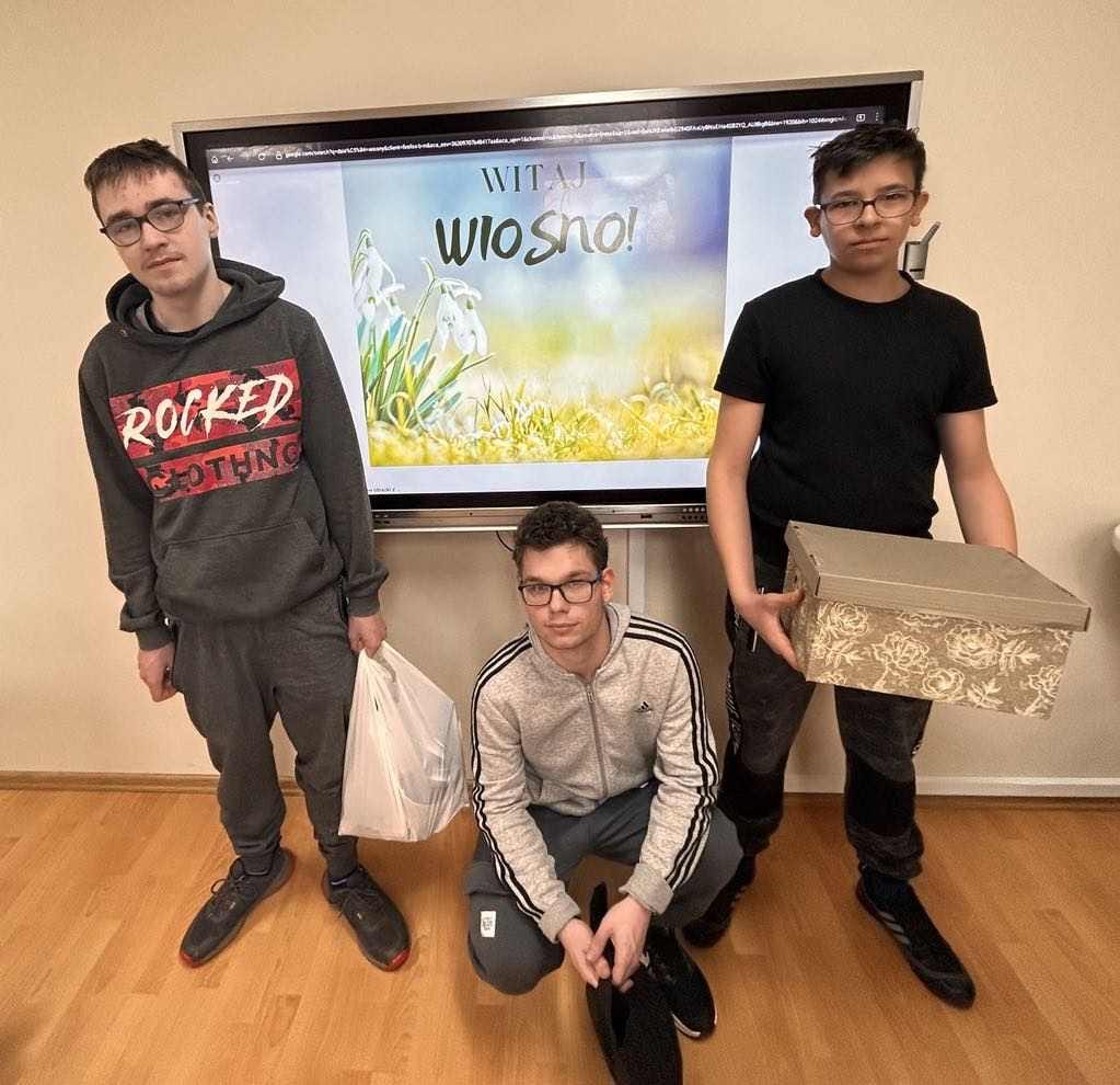Pod ścianą stoi grupa osób