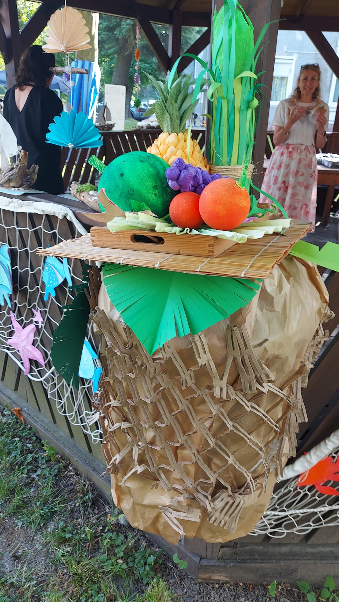 Po lewej kolorowe ozdoby. Po prawej stronie stoi osoba