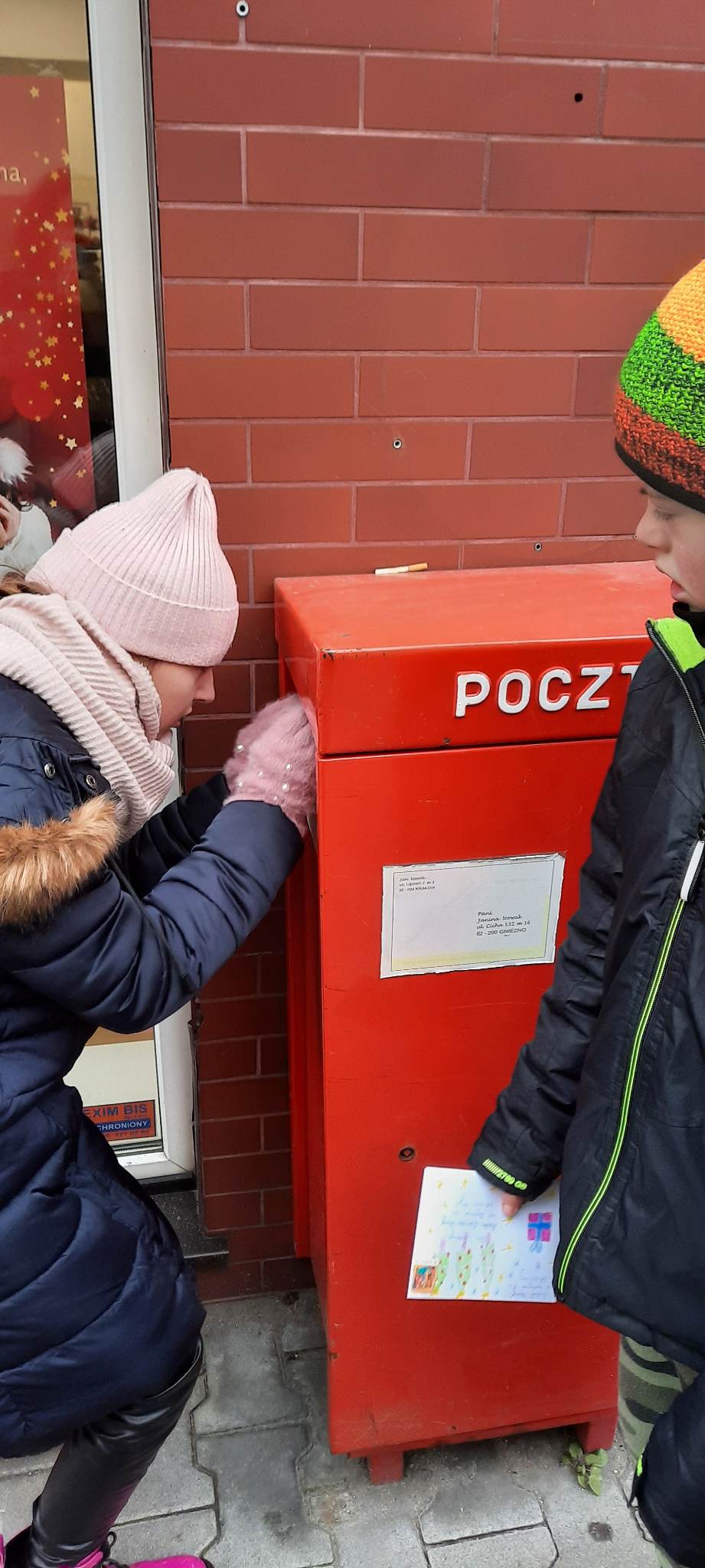 na środku skrzynka na listy, po bokach osoby