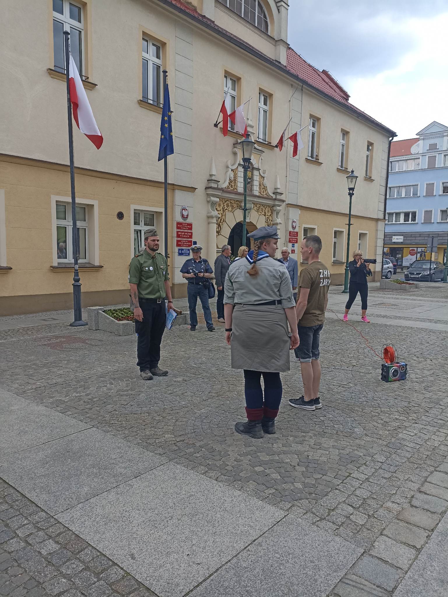 Przed budynkiem stoi grupa osob