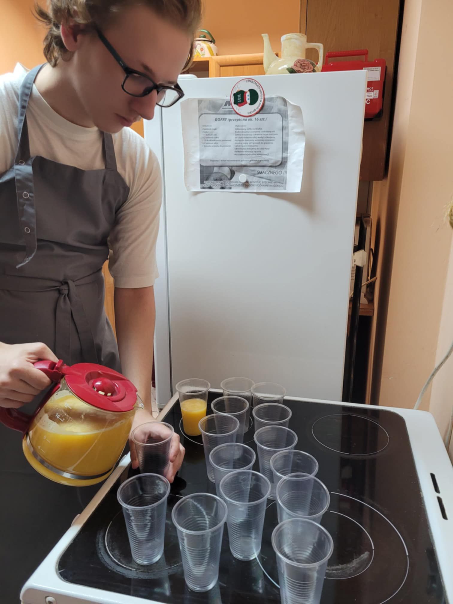 Zdjęcie przedstawia osobę , kubki, czajnik szklany