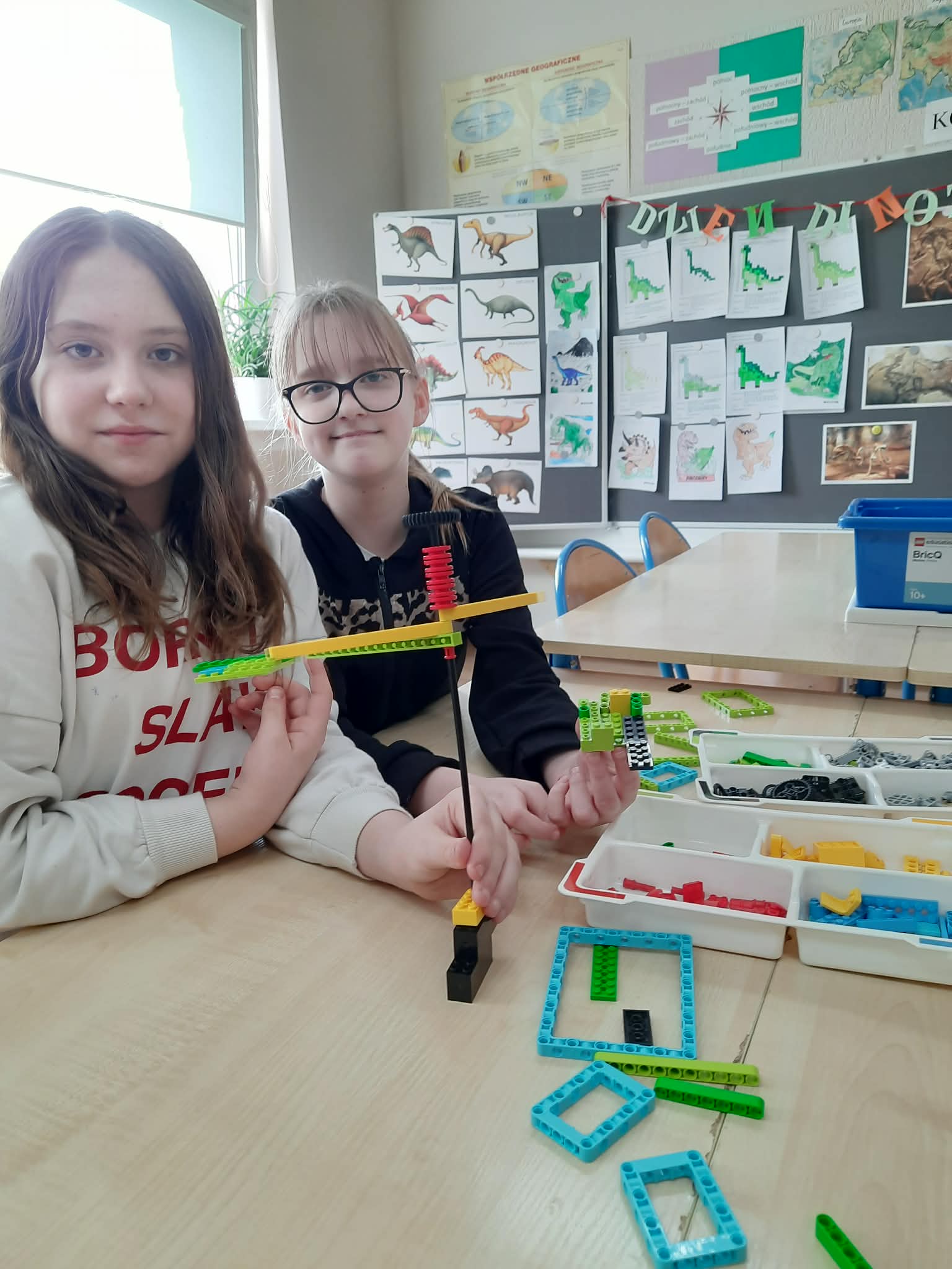 Na obrazku widać :2 osoby , stol, klocki.