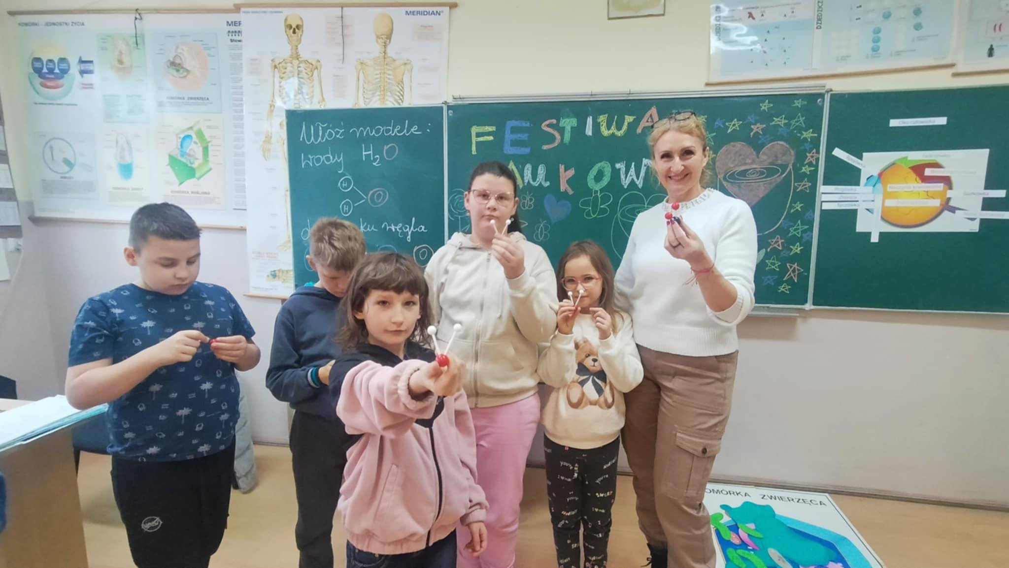 Na obrazku widać: osoby, tablicę, plansze